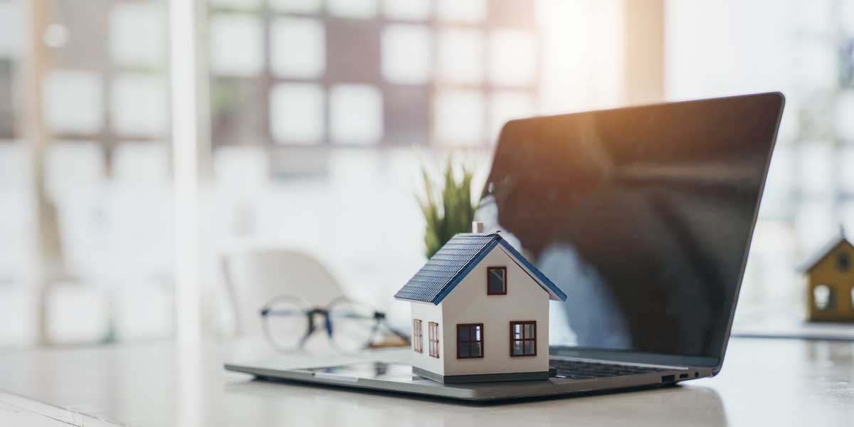 A decorative house sitting on a laptop